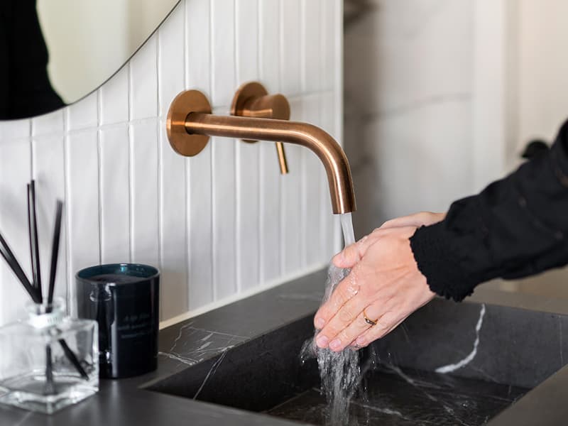 Kranen van geborsteld koper en een houten meubel in de badkamer