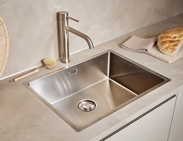 Kraan en spoelbak in een greige keuken