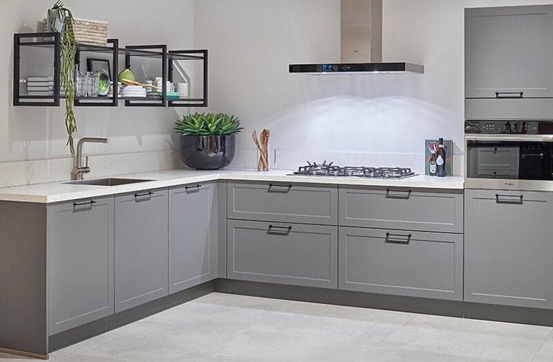 Grijze industriële keuken met wit werkblad en zwarte handgrepen